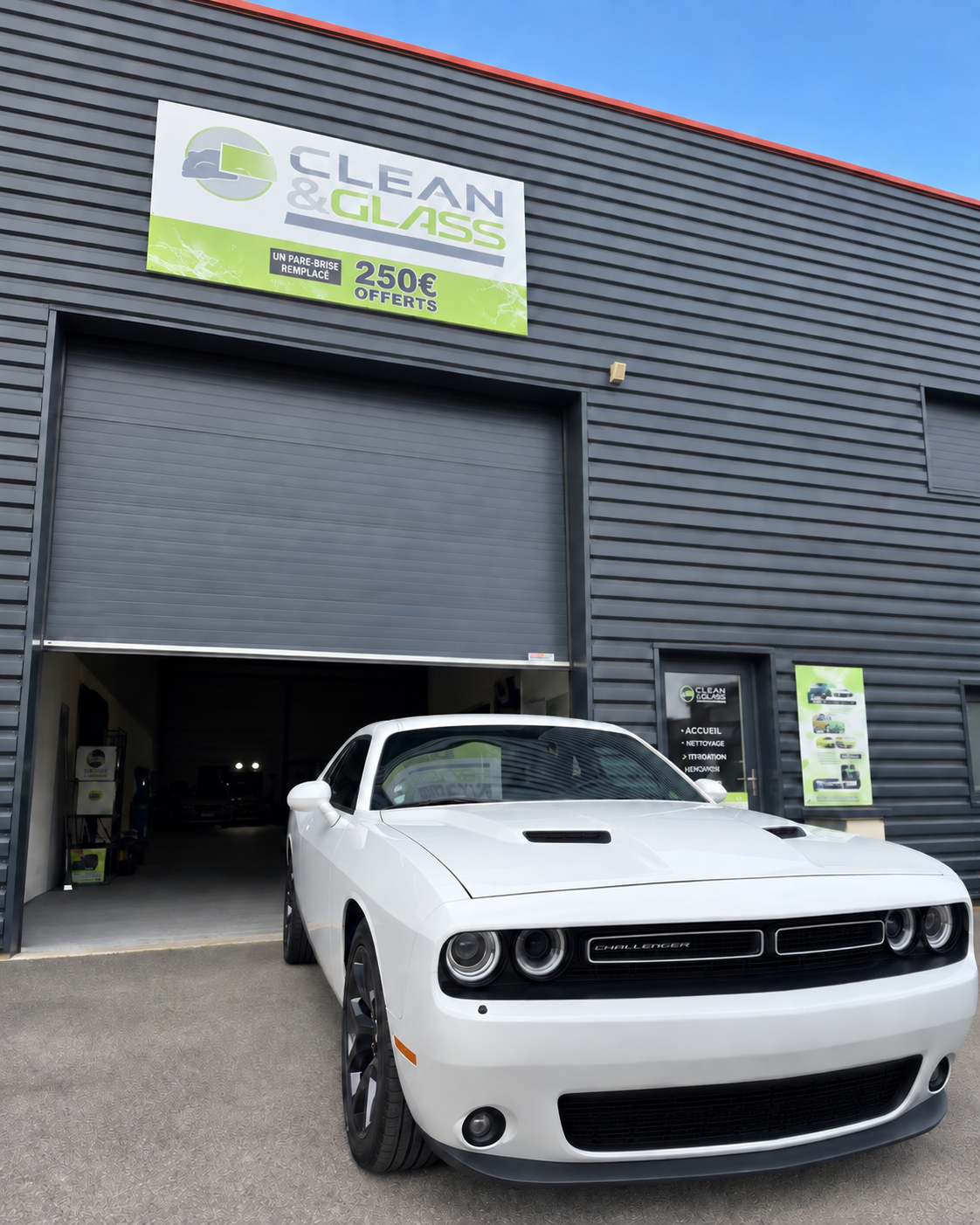 Dodge Challenger blanche devant le centre Clean & Glass, sous un ciel bleu, avec l’offre 250 € offerts sur l’enseigne.